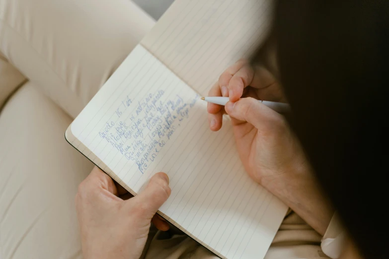 a woman with a pen is writing notes in an open notebook