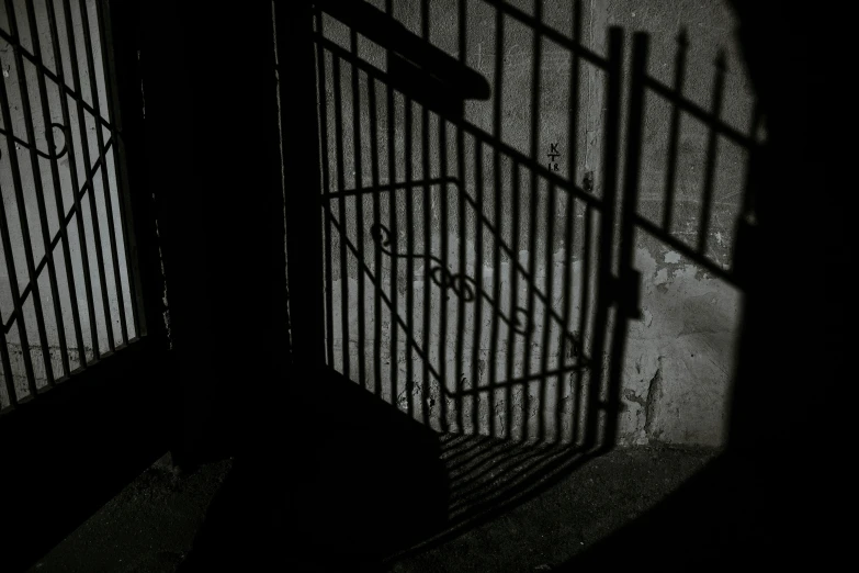 shadow of an open gate and sign on a sidewalk