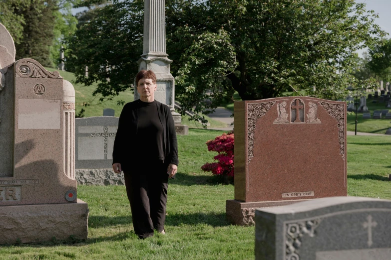 a woman standing next to headstones in a cemetery
