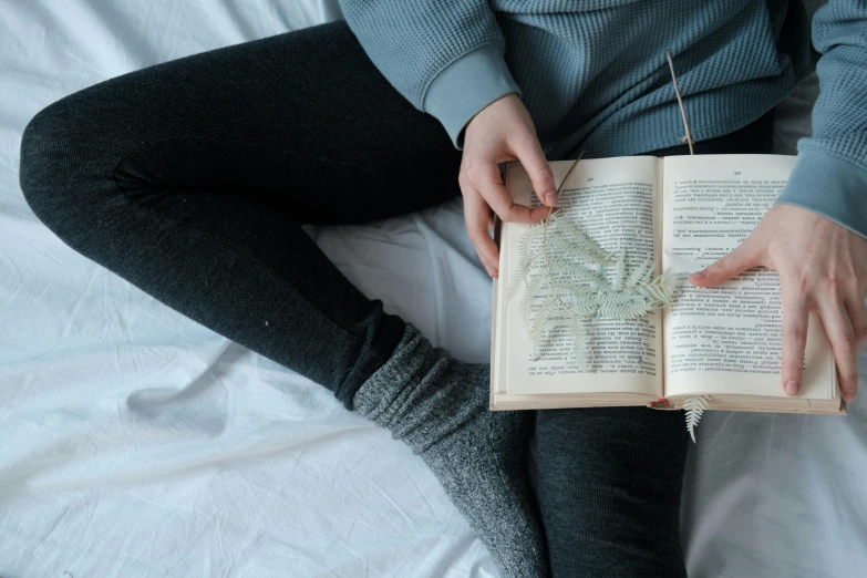 a person sits on their bed reading an old book