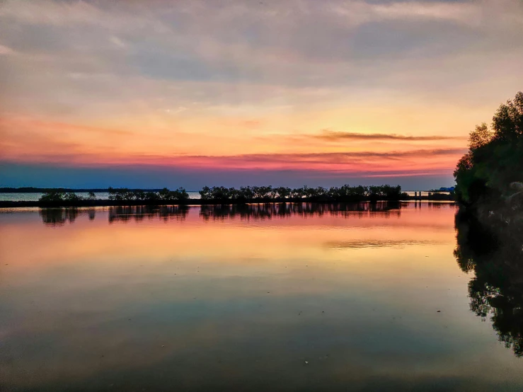 a lake during sunset with trees reflecting in the water