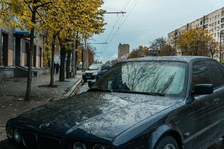 a bmw car covered in rain next to a street