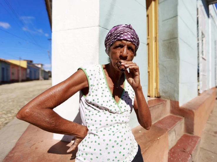 a woman smokes an item near a house