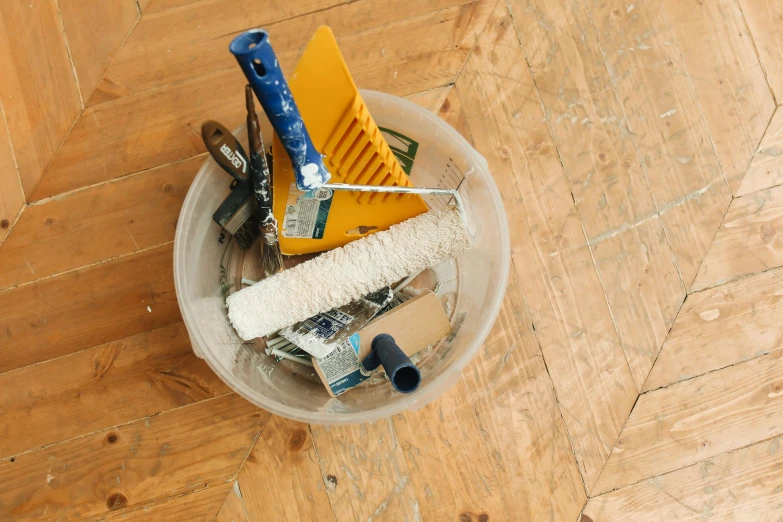 a bucket filled with various items that include brush, sponge and a tube