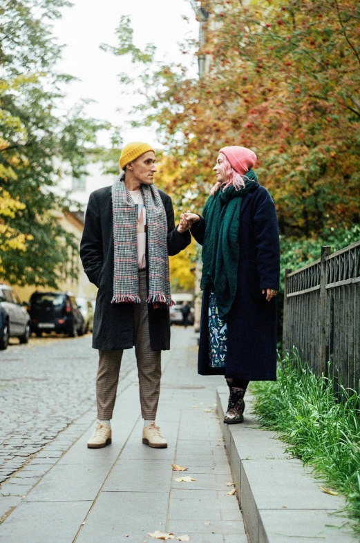 two elderly people standing on sidewalk near tree