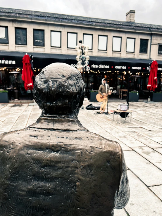 a man statue sitting outside an outdoor shopping mall