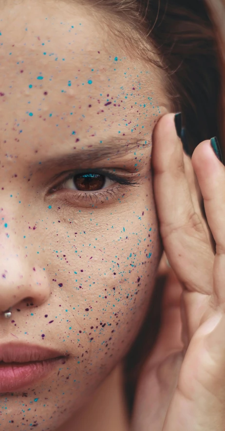 a woman has blue and pink speckles on her face
