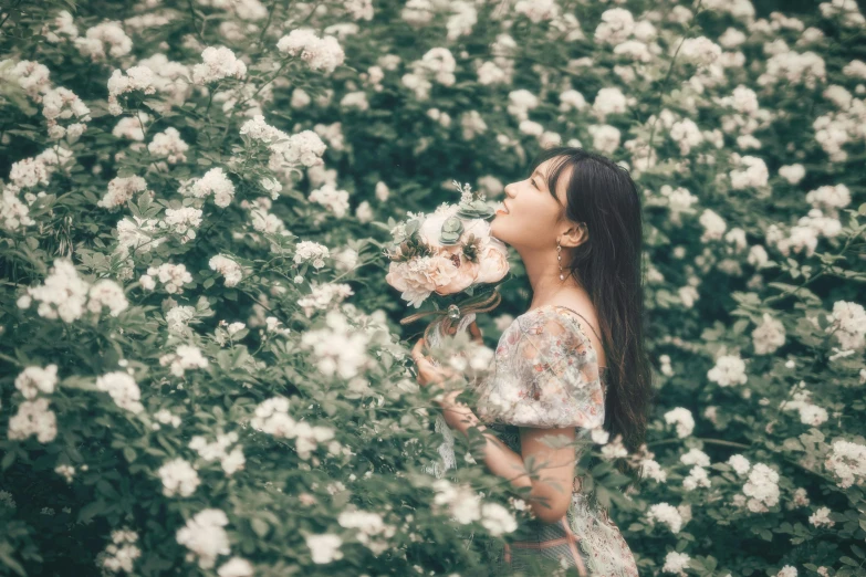 a woman standing in front of bushes with flowers