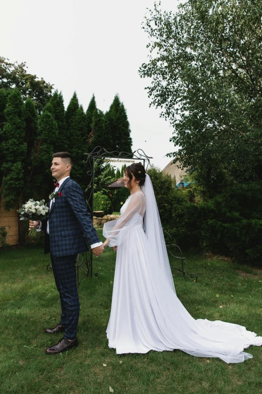 the bride and groom stand close together on the grass