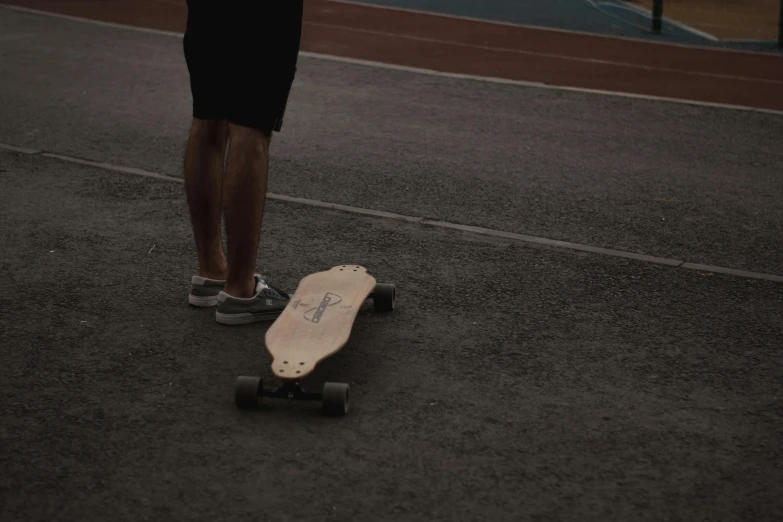 a person stands on the ground with their skateboard