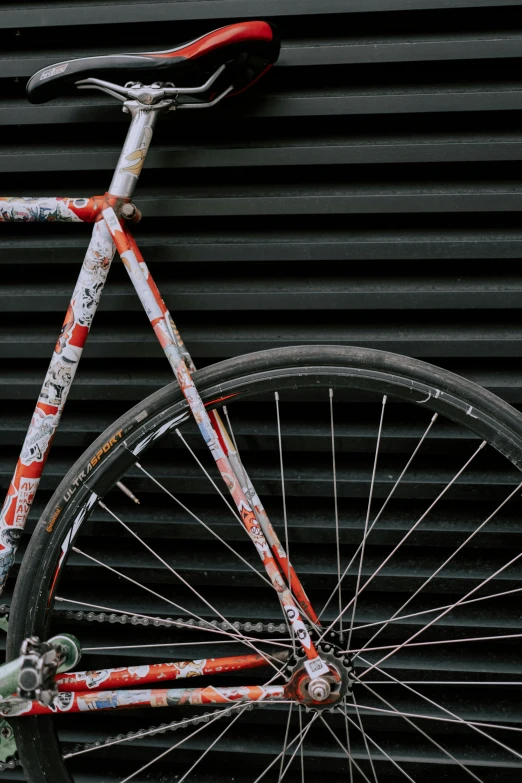 a bicycle painted with paint is parked against a metal wall