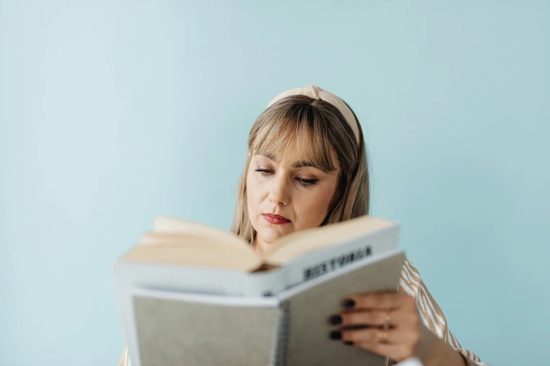 the woman is reading a book that she's holding