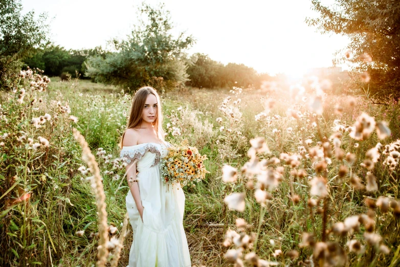 the young bride walks through a field holding a bouquet