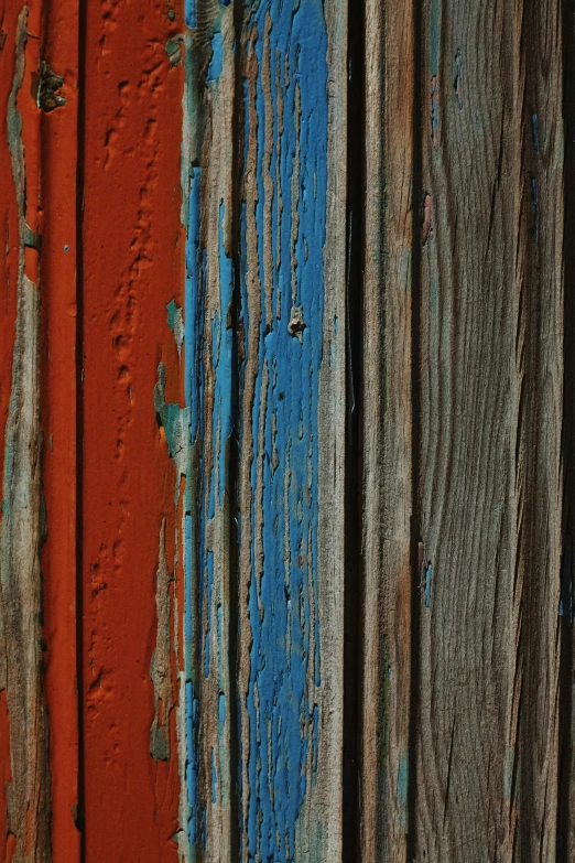 the side of an old weathered wooden building, showing colorful paint on it