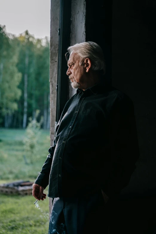 a older man with a white beard is looking out a window