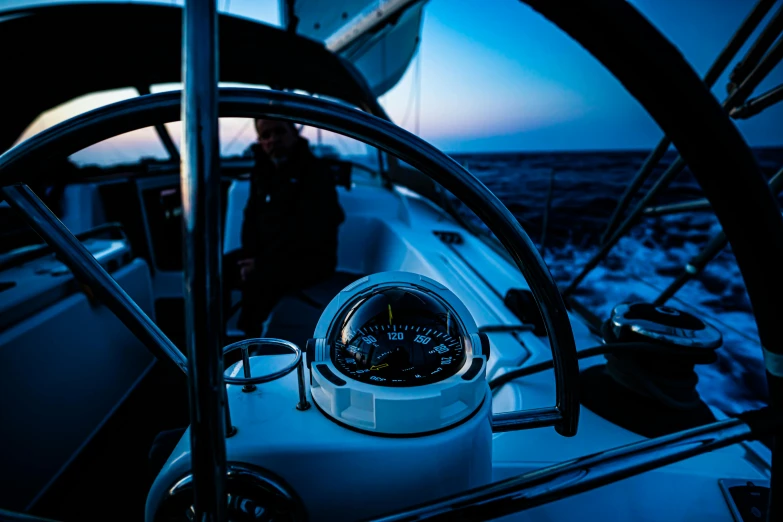 the dashboard of a boat during sunset with a male sailor nearby