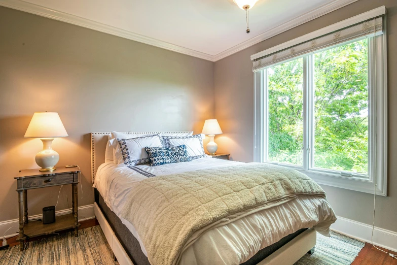 a bed sitting underneath two large windows in a bedroom