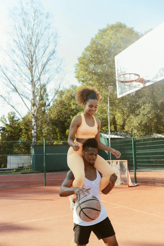 a man standing on top of a woman while holding a basketball