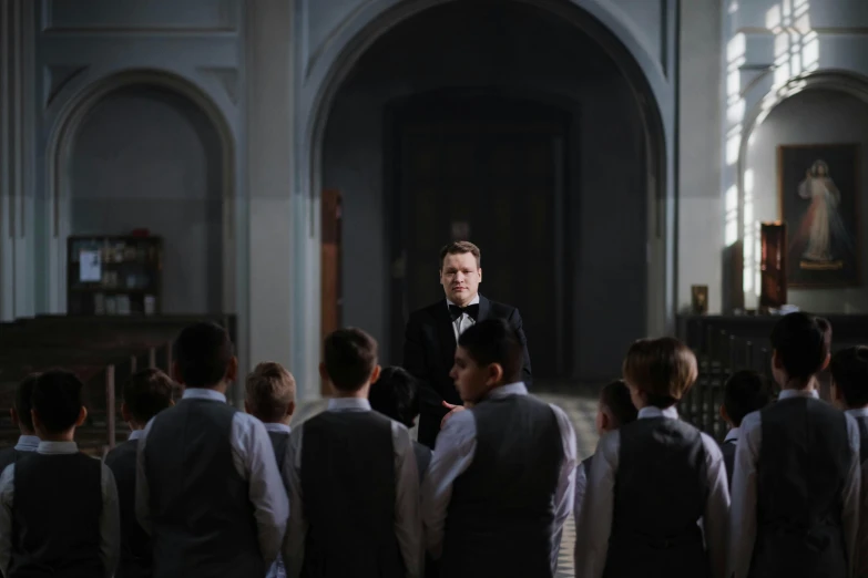 an image of a man in a suit talking to a bunch of people