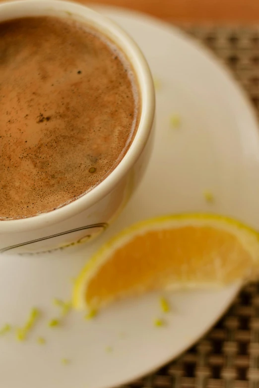 a orange slice sitting in front of a cup of cocoa