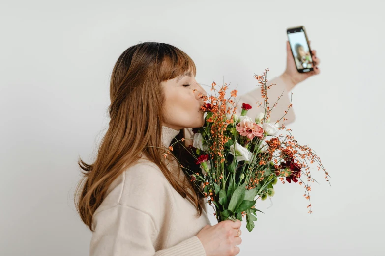 the woman holds a bouquet and takes her picture