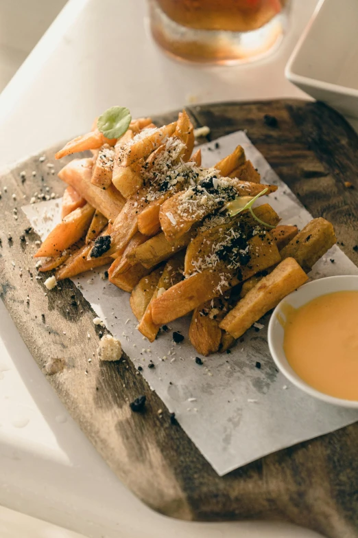 fried french fries are sitting on a wooden tray next to a bowl with dipping sauce