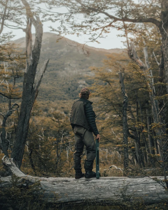 the man stands on a log in a wooded area