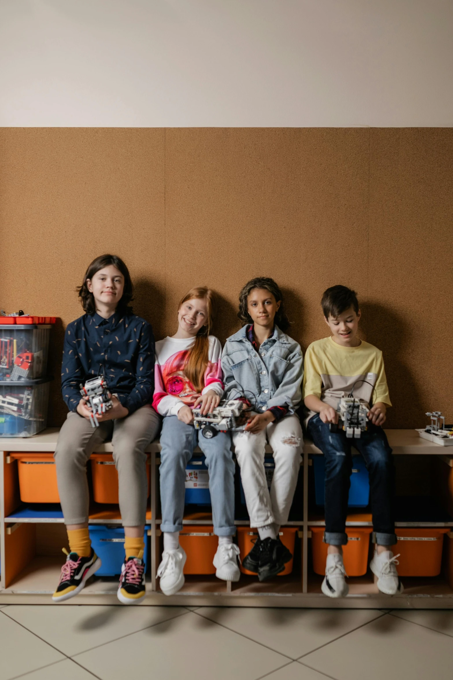 children sitting on a bench with their toys in front of them