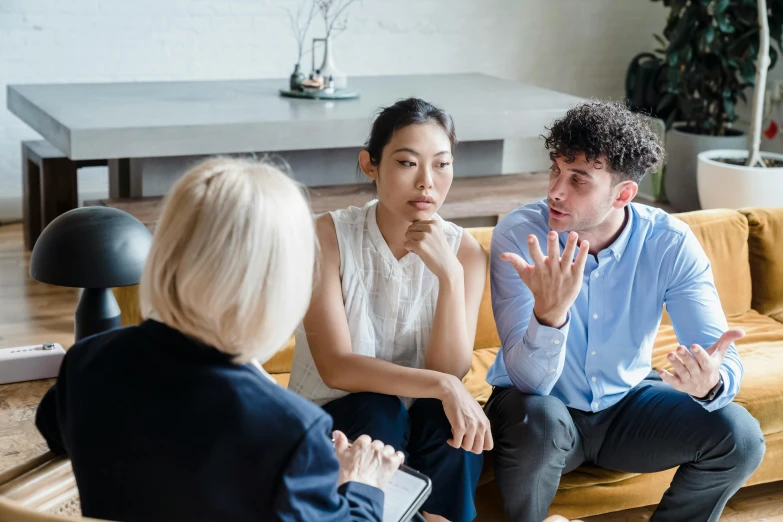 a man talking with two women on a couch