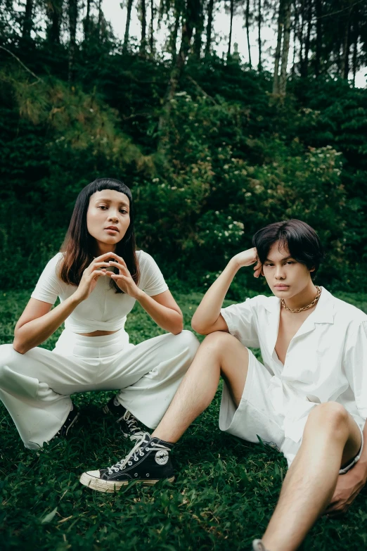 two girls are sitting outside in the grass