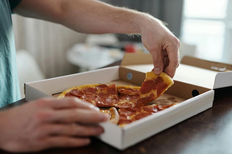 a person  a slice into a box with pizza in it
