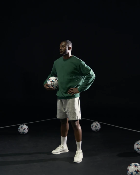 an african american man poses with soccer balls in the dark