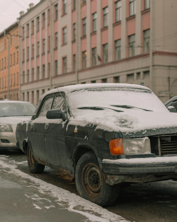 an old car is parked in a snow storm