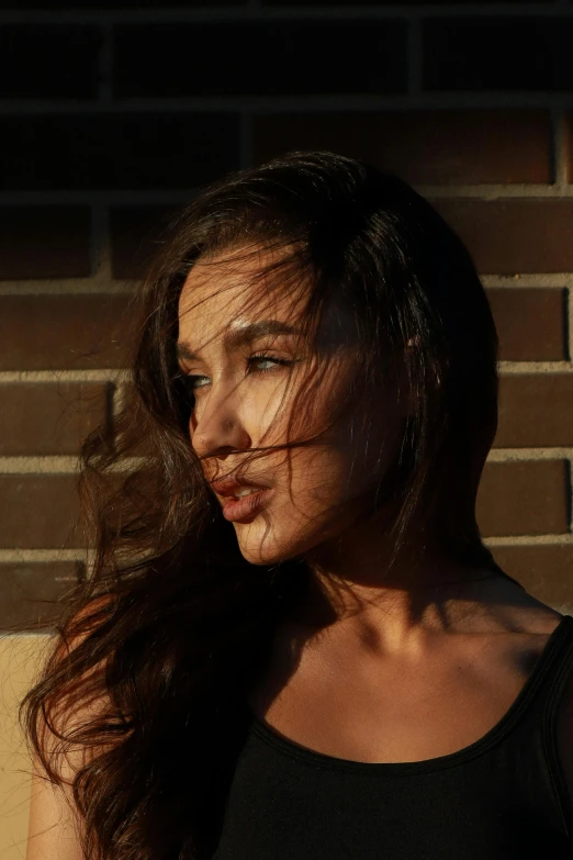 a young woman standing in front of a brick wall