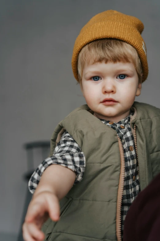 young child with blue eyes wearing vest and hat