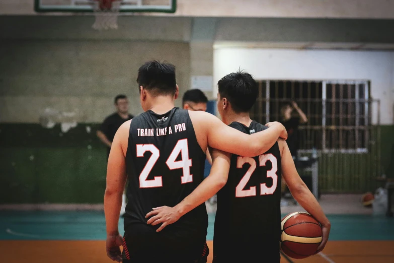 two men in black and white uniforms stand on a basketball court