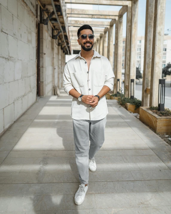 a man standing on the sidewalk near some big pillars