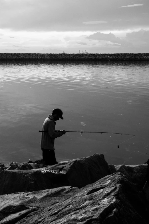 a man fishing on the water from rocks