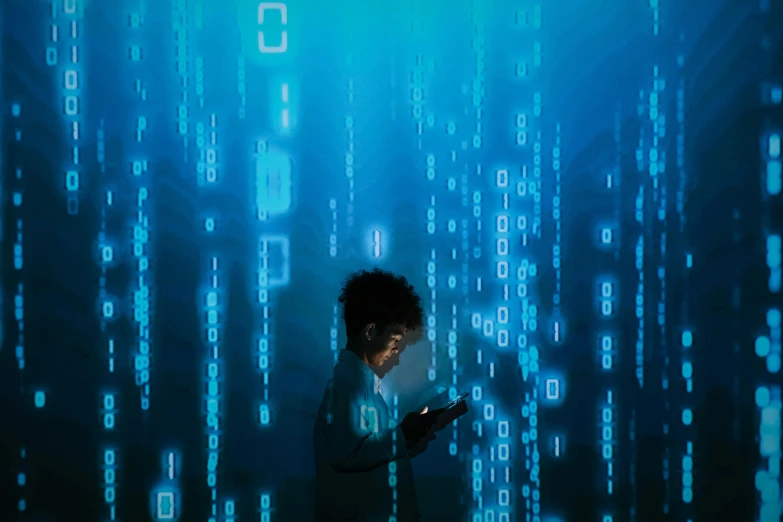 a man standing in front of a computer screen covered in blue code numbers