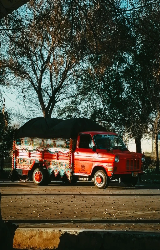 an old red truck driving down a street