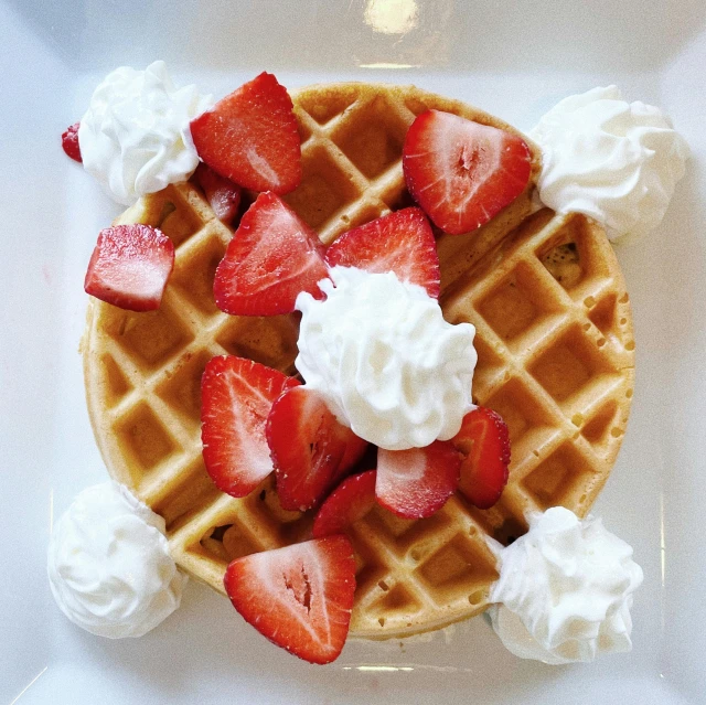 a waffle with whipped cream and sliced strawberries