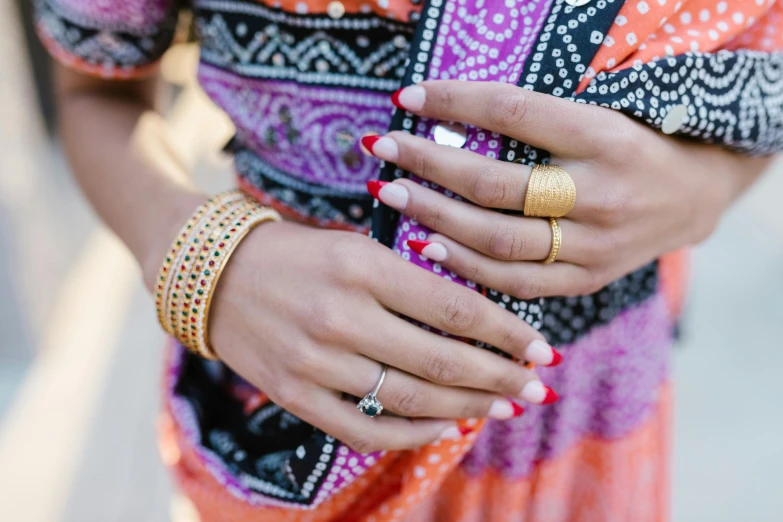 a woman in a colorful dress with gold rings