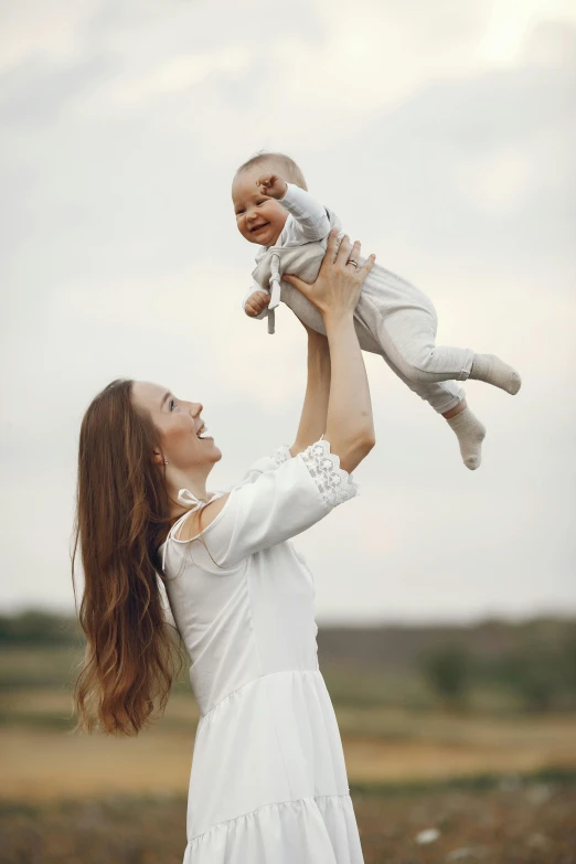 a woman holds her baby up high in the air for a s