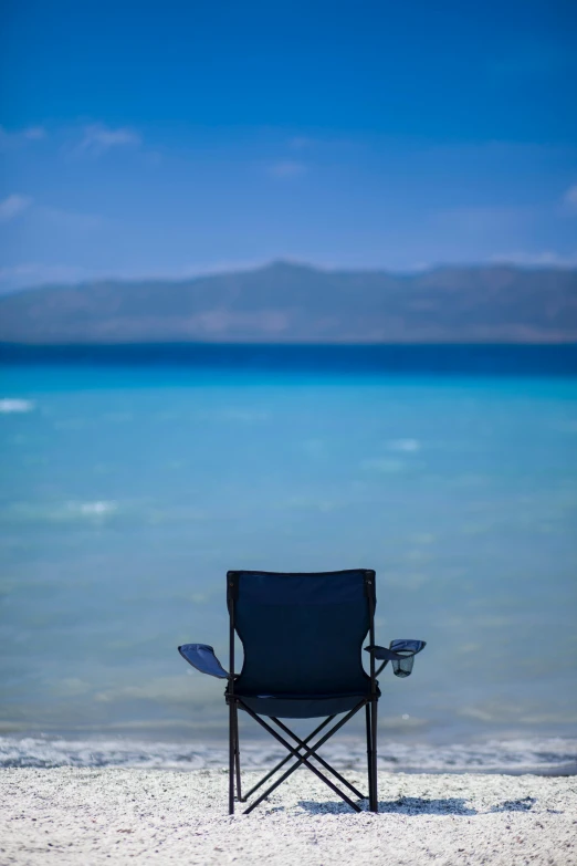 a lone chair on the beach looking out at the water