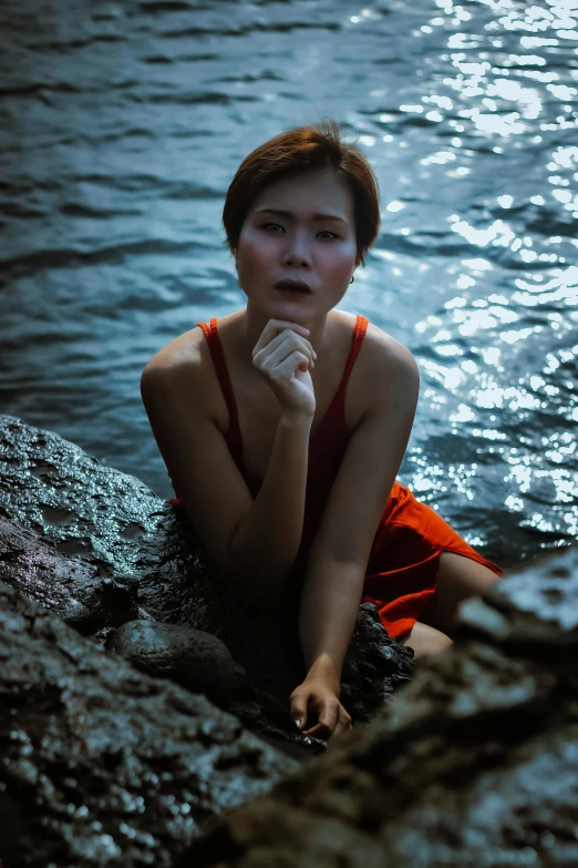 a woman in red sits on the water edge