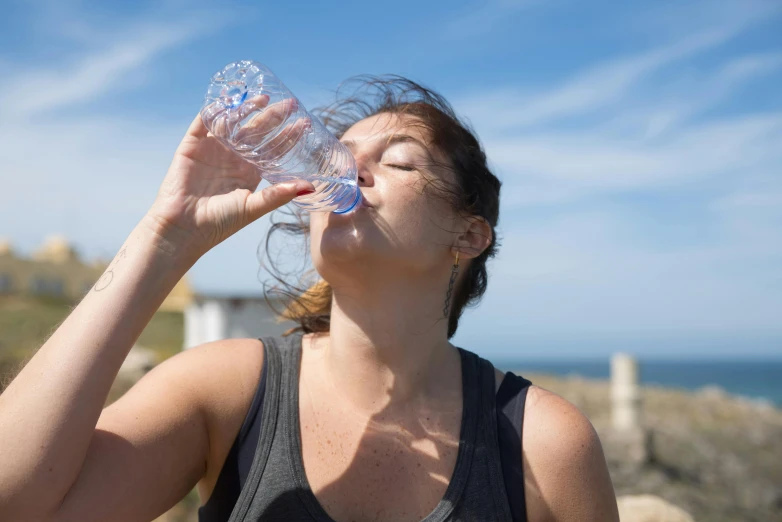 woman drinking water with a view of ocean in the background