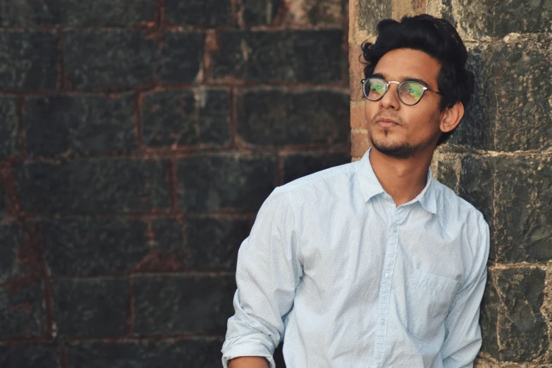 a young man standing against a wall with a building in the background