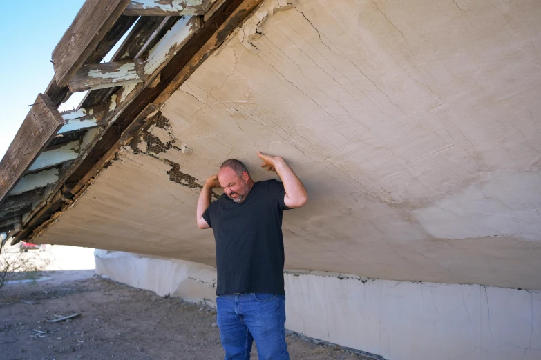 the man is leaning against a wall holding his head