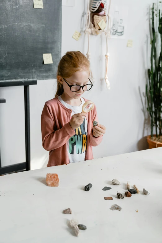 girl holding small pieces of glass while standing at table