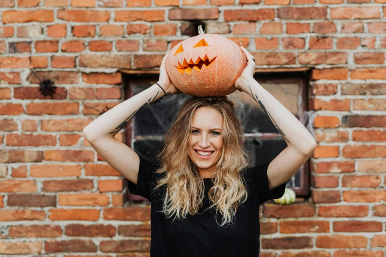 a woman is holding a pumpkin in front of her face